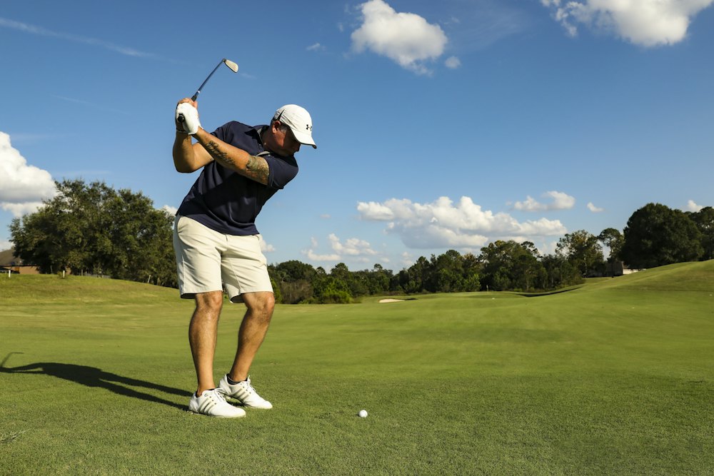 A golfer taking a swing on a fairway on a clear day