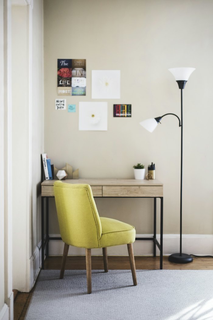 Small white desk with a yellow chair and floor lamp