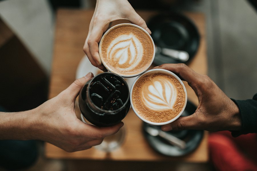 Friends toasting with cups of latte in a café
