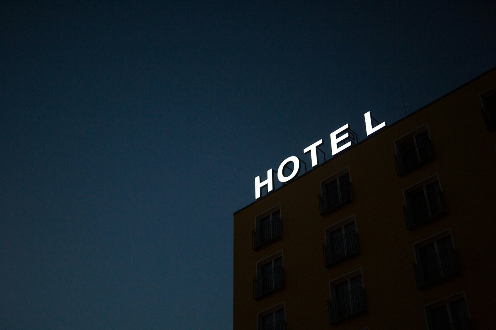 Brick hotel facade with a lit HOTEL sign at dusk