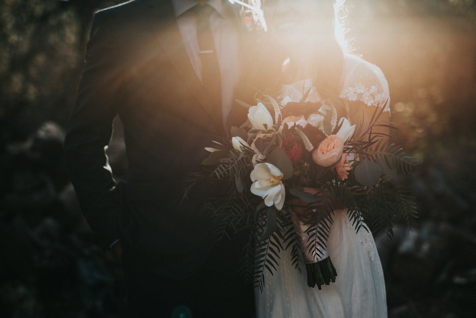 Wedding bouquet of white flowers held in warm, soft light