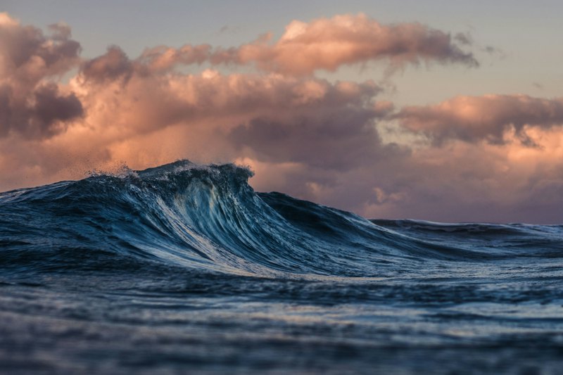 Blue ocean wave curling under a cloudy sky