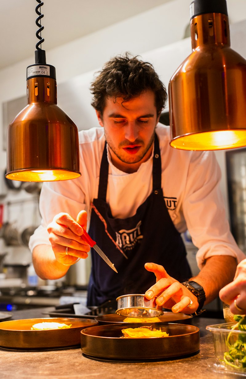 Chef finishing a plate under copper pendant lamps