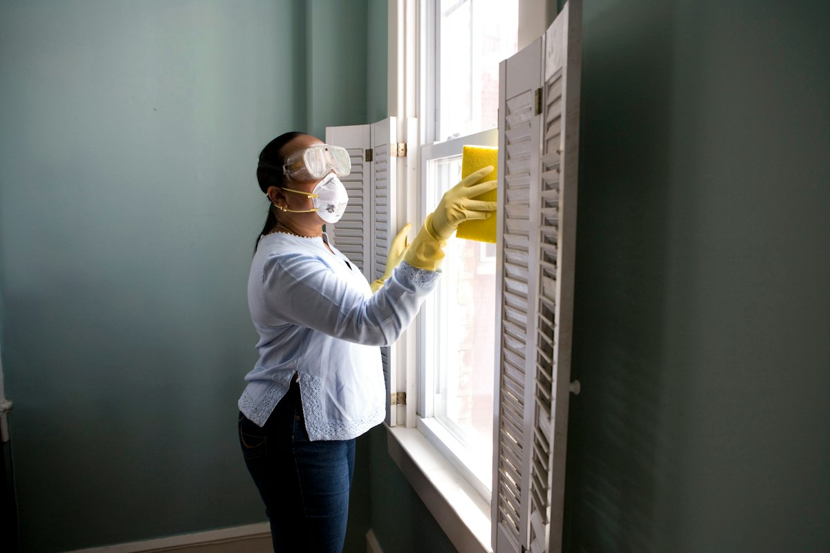 Person in yellow gloves wiping a kitchen counter