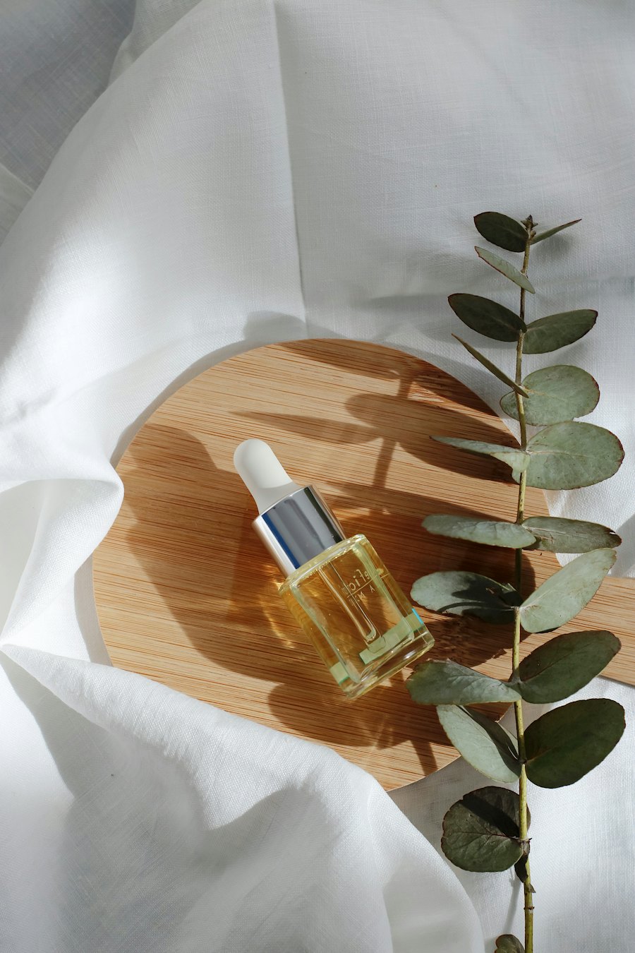 Oil dropper bottle on a wooden board with eucalyptus